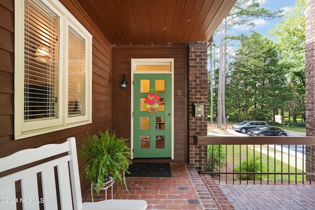 doorway to property with a porch and brick siding