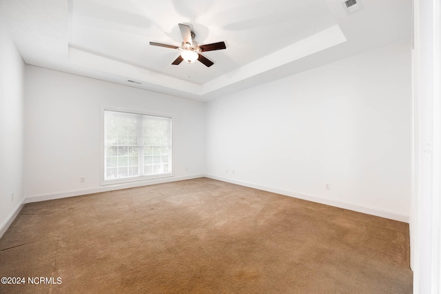 carpeted empty room with a tray ceiling and ceiling fan