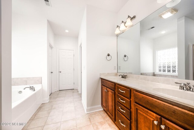 bathroom with a tub to relax in, vanity, and tile patterned flooring