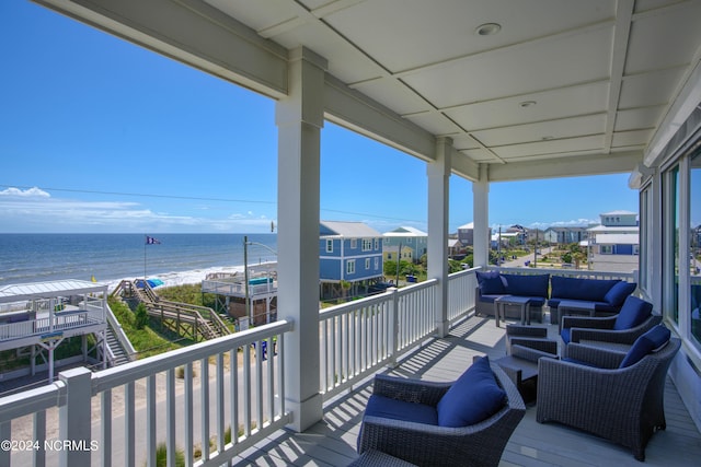 balcony featuring an outdoor living space, a water view, and a view of the beach