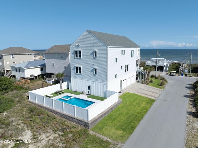 back of house with a garage, a water view, and a lawn