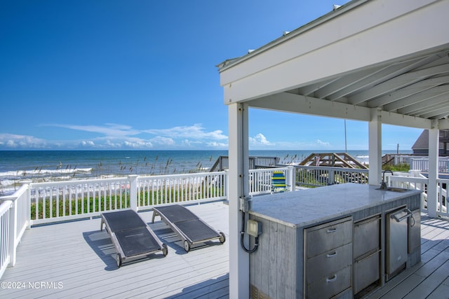 wooden terrace featuring a water view, outdoor dry bar, and a view of the beach