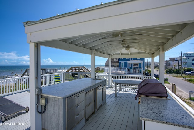 deck featuring a water view, exterior bar, and ceiling fan