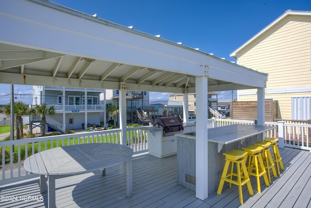 wooden terrace featuring outdoor dry bar and area for grilling