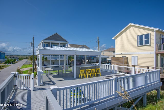 rear view of property featuring a deck, metal roof, and outdoor dry bar