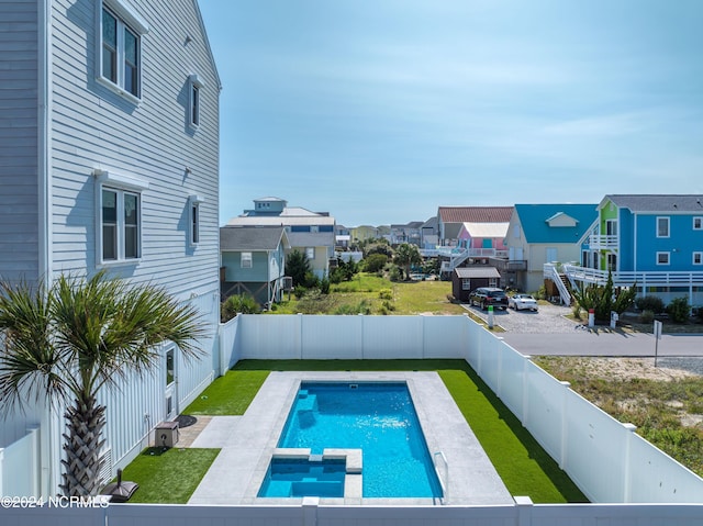 view of pool featuring a residential view, a pool with connected hot tub, and a fenced backyard