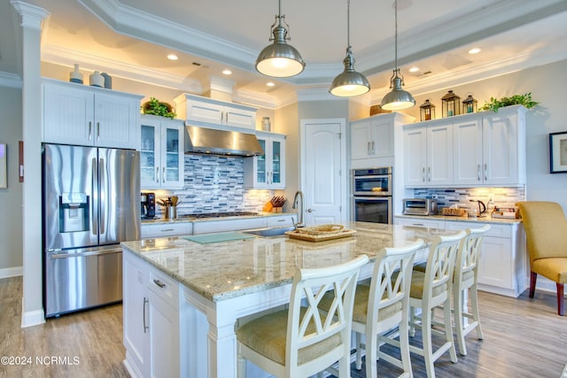 kitchen with a center island with sink, white cabinets, stainless steel appliances, a sink, and exhaust hood