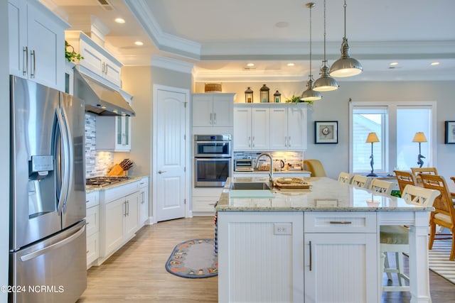 kitchen with a center island with sink, appliances with stainless steel finishes, and a breakfast bar