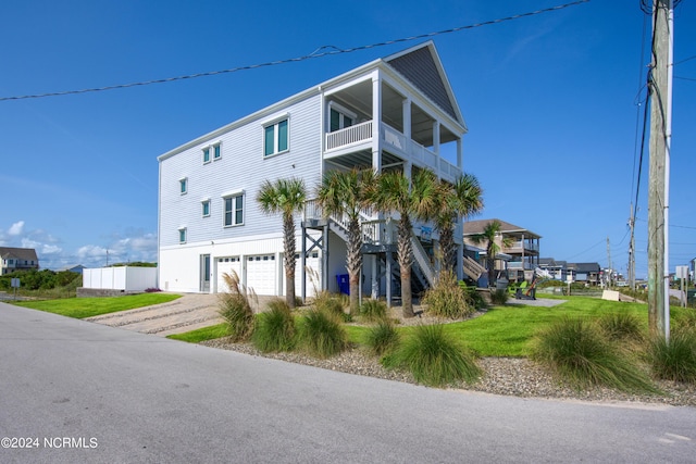 view of front of home featuring a garage, a front yard, driveway, and a balcony