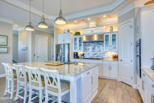 kitchen with extractor fan, a kitchen island with sink, stainless steel appliances, white cabinets, and glass insert cabinets