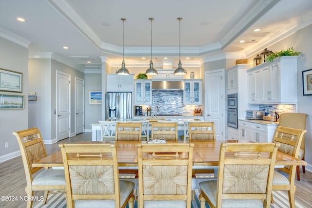 kitchen featuring pendant lighting, a center island with sink, glass insert cabinets, stainless steel fridge, and a kitchen breakfast bar