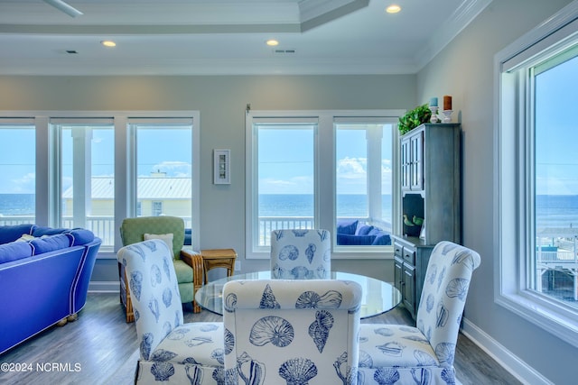 dining space with a wealth of natural light, a water view, crown molding, and wood finished floors