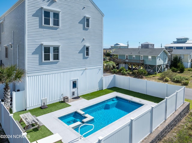 rear view of house with a residential view, a fenced backyard, and a pool with connected hot tub