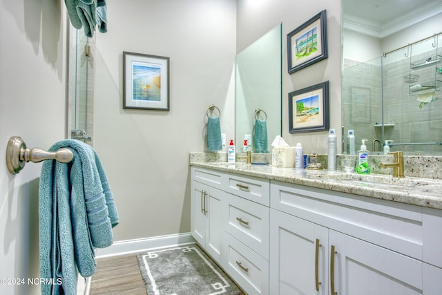 bathroom with wood finished floors, vanity, baseboards, a shower stall, and crown molding