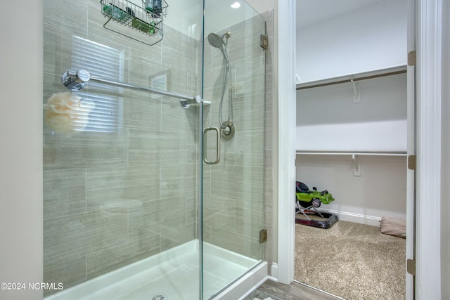 bathroom with a spacious closet, a stall shower, and baseboards