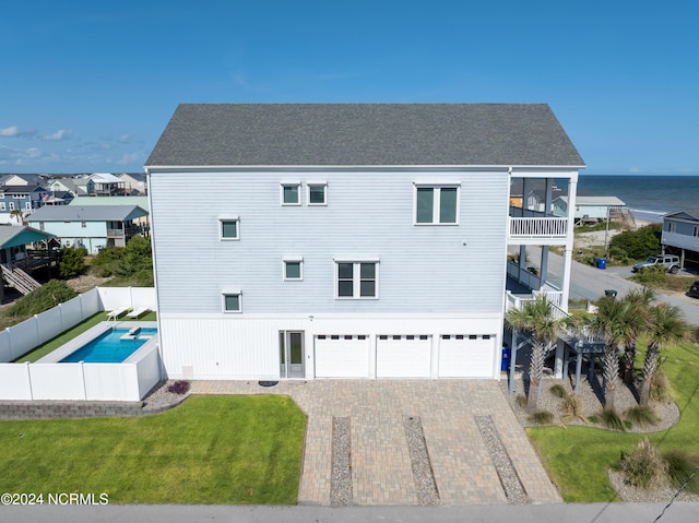 exterior space with decorative driveway, a water view, a lawn, a balcony, and fence private yard