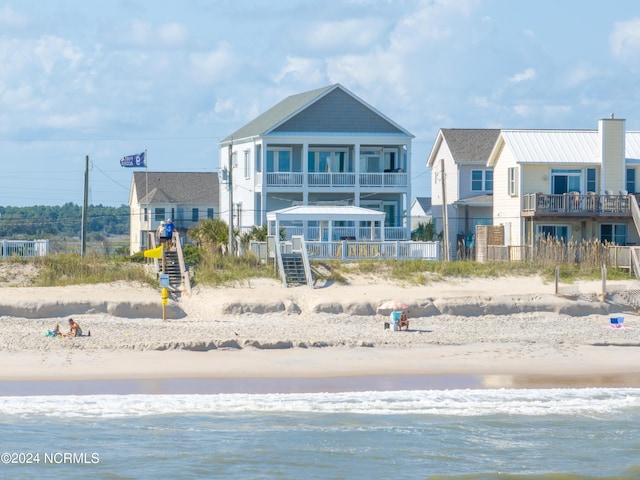 back of property featuring a water view and a view of the beach