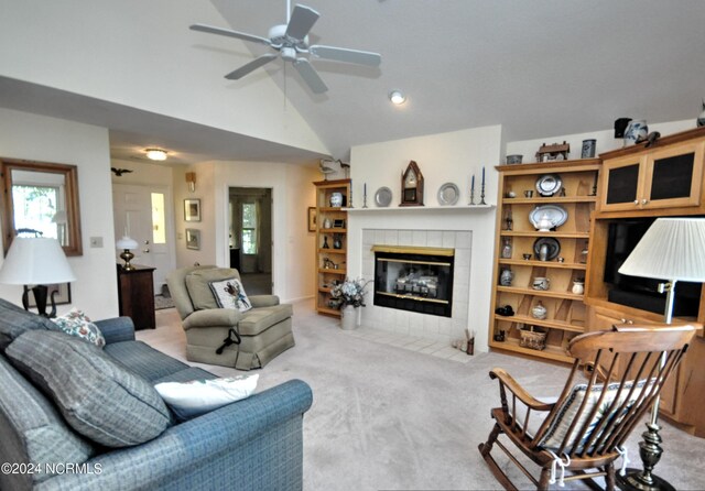 carpeted living room with lofted ceiling, ceiling fan, and a tile fireplace