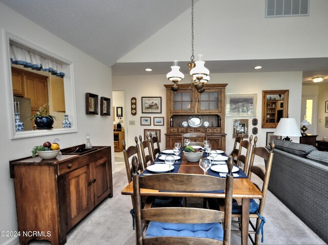 carpeted dining room with high vaulted ceiling and an inviting chandelier