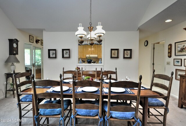 dining area featuring an inviting chandelier, light carpet, and vaulted ceiling