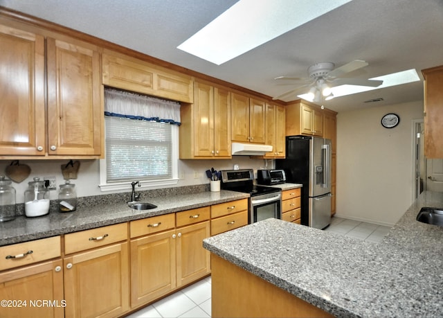 kitchen with light tile patterned floors, a skylight, stainless steel appliances, under cabinet range hood, and a sink