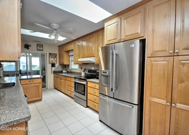 kitchen with a skylight, light tile patterned floors, stainless steel appliances, sink, and ceiling fan