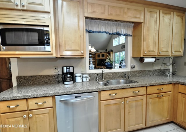 kitchen with appliances with stainless steel finishes, light stone counters, light tile patterned floors, and sink