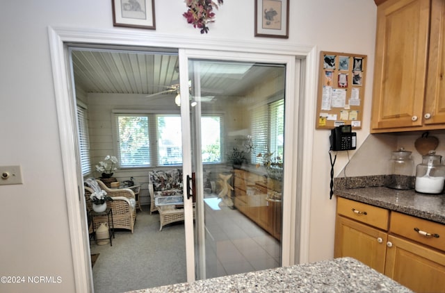 interior space with carpet, dark stone counters, and a ceiling fan