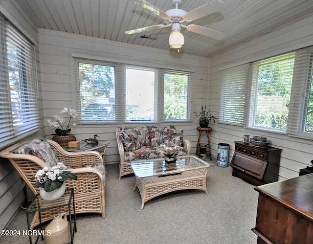 living room with a ceiling fan, carpet, wooden ceiling, and wooden walls