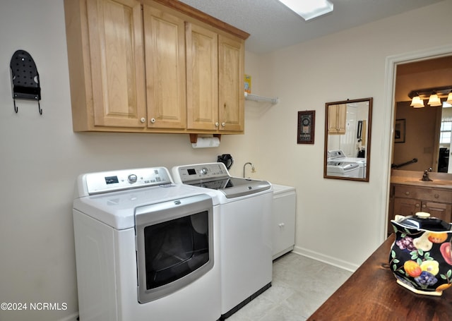 clothes washing area with baseboards, cabinet space, independent washer and dryer, and a sink