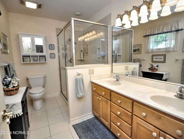 bathroom with tile patterned floors, toilet, a shower with door, and vanity