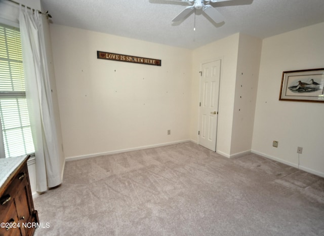 unfurnished bedroom featuring a textured ceiling, ceiling fan, and light colored carpet