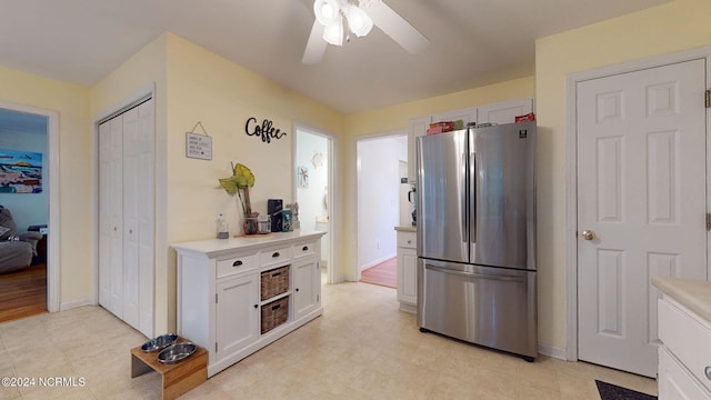 kitchen featuring stainless steel fridge, white cabinetry, and ceiling fan