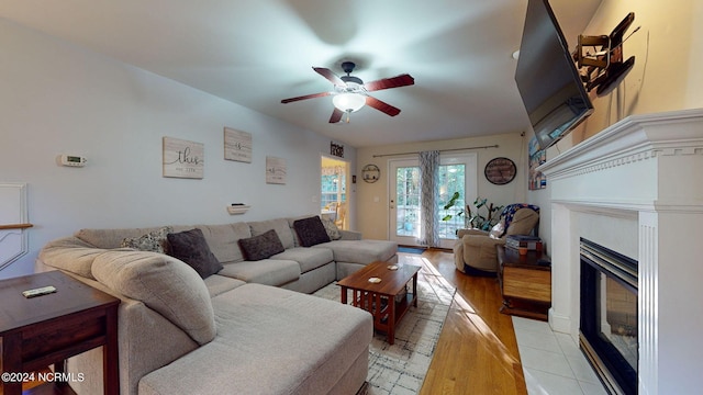 living room featuring light wood-type flooring, ceiling fan, and a fireplace