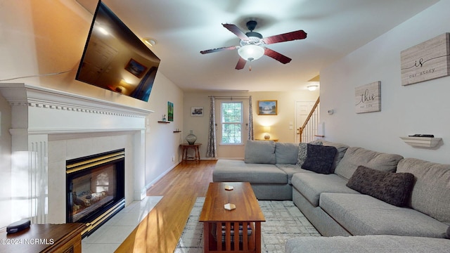 living room featuring light hardwood / wood-style flooring, ceiling fan, and a fireplace