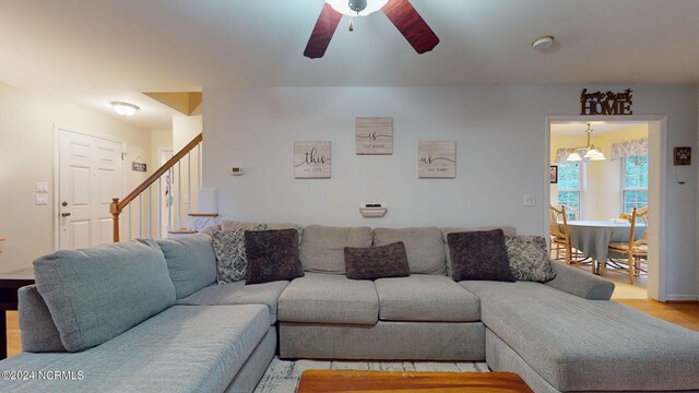 living room with ceiling fan with notable chandelier and light wood-type flooring