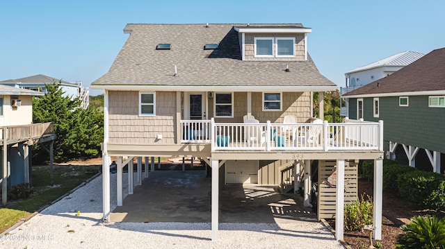 rear view of property with gravel driveway, stairway, a carport, and roof with shingles