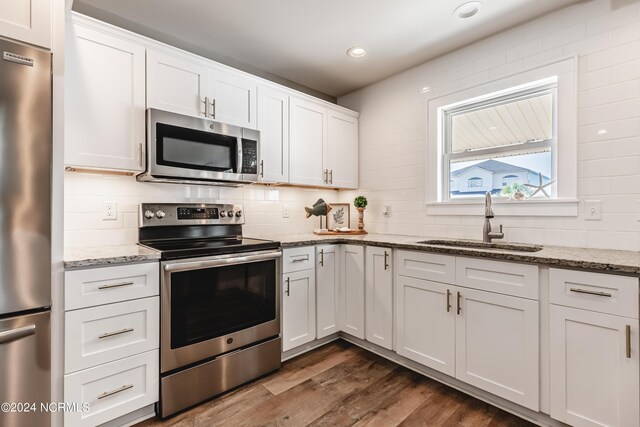 kitchen with white cabinetry, backsplash, sink, dark hardwood / wood-style floors, and appliances with stainless steel finishes