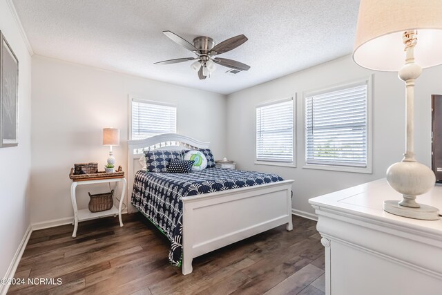 bedroom with multiple windows, a textured ceiling, and dark hardwood / wood-style floors