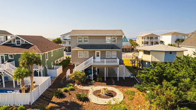 back of property featuring stairs, a residential view, a shingled roof, and a fenced backyard