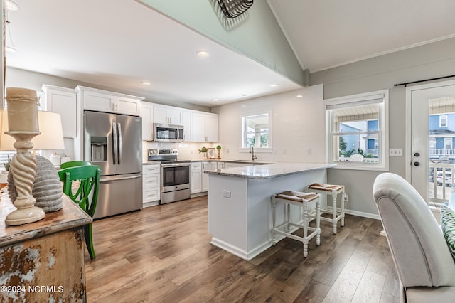 kitchen with stainless steel appliances, white cabinetry, lofted ceiling, dark hardwood / wood-style floors, and kitchen peninsula