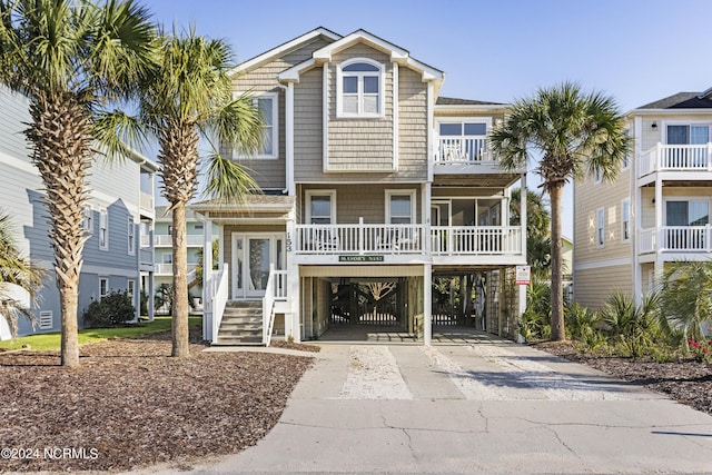 raised beach house with driveway, a balcony, and a carport