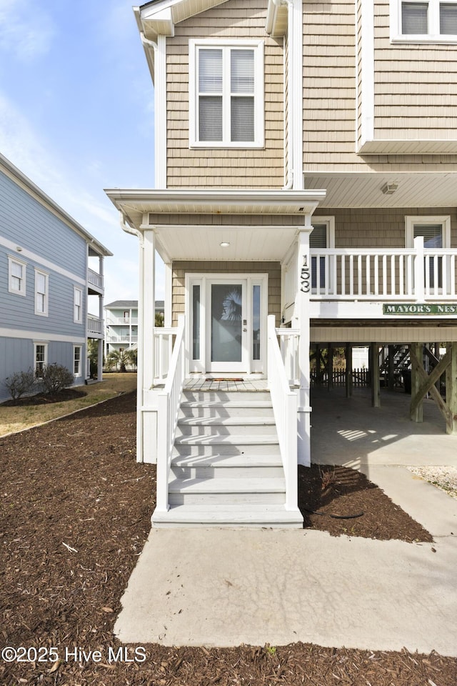 view of exterior entry featuring covered porch and a carport