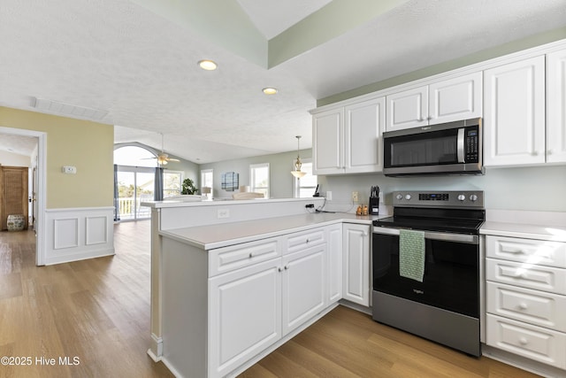 kitchen with stainless steel appliances, light wood-style floors, a peninsula, and white cabinets