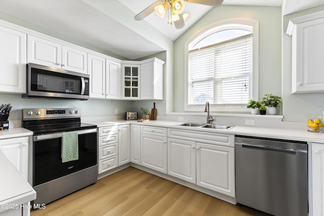 kitchen featuring stainless steel appliances, light wood-style floors, white cabinetry, and a sink