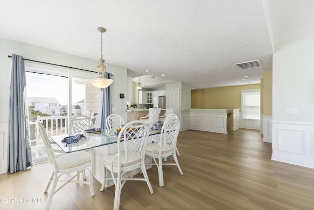 dining room with a healthy amount of sunlight, light wood-style floors, visible vents, and a decorative wall