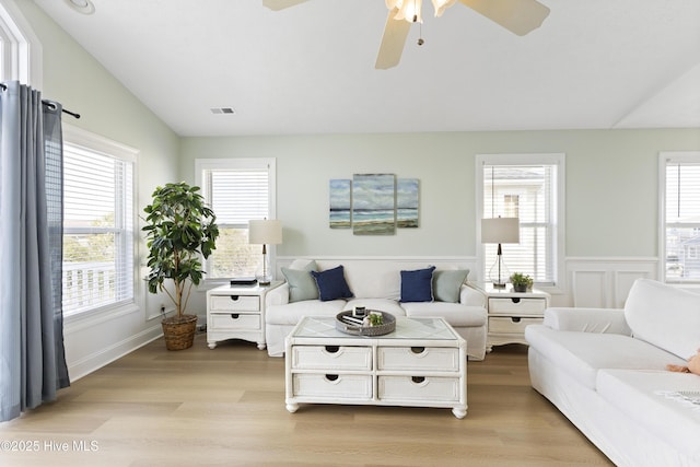 living area featuring vaulted ceiling, light wood finished floors, and a healthy amount of sunlight