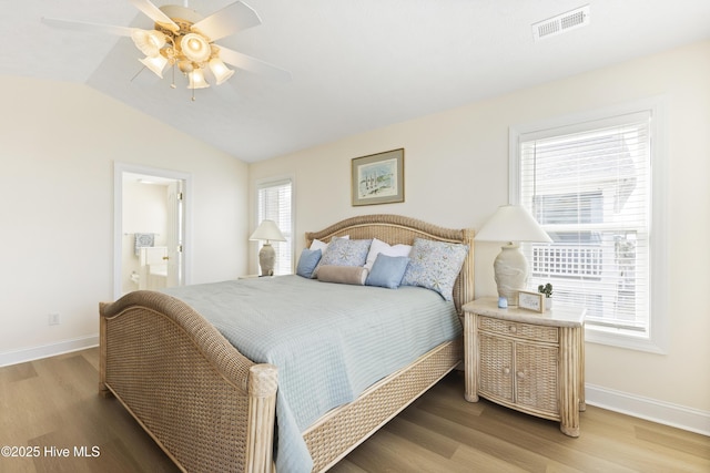 bedroom with vaulted ceiling, wood finished floors, visible vents, and baseboards