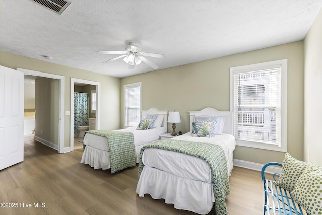 bedroom with a textured ceiling, multiple windows, wood finished floors, and visible vents