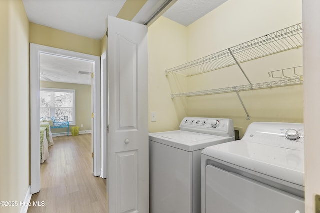 laundry area featuring laundry area, light wood-type flooring, independent washer and dryer, and baseboards